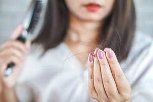 Woman examining how much hair she's lost after brushing her hair